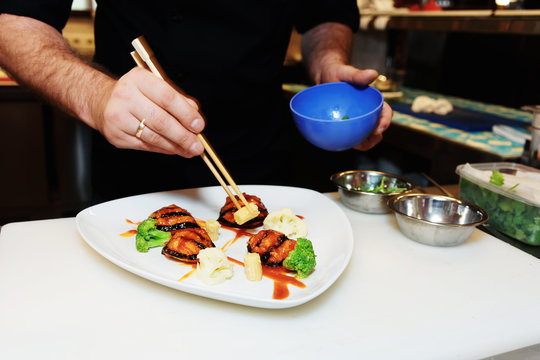 Chef is decorating a dish with chopsticks, toned