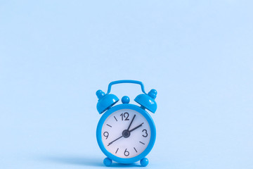 Small alarm clock on blue background