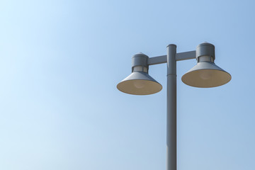 Light tower and black lamp with bright blue sky background.
