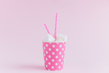 Paper cup with sugar cubes and drinking straws isolated on rose background creative food minimalistic concept