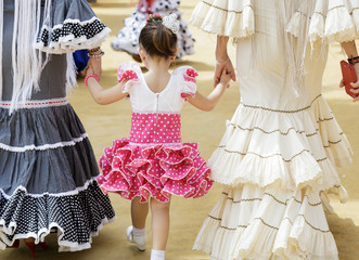 Family in traditional dress taking a walk and enjoying at the Seville's April Fair. 