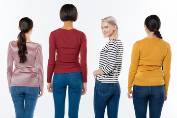 Obraz premium Positive attitude. Joyful nice blonde woman turning to you and smiling while standing among her friends