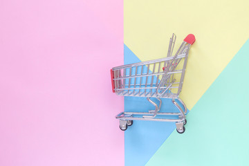 Flat lay of shopping cart on pastel background minimalistic concept.