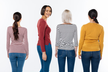 Obraz premium Social project. Happy positive young woman standing among her friends and turning to you while smiling