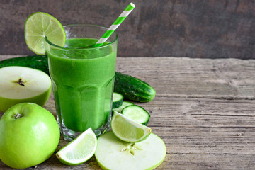 green smoothie in a glass with spinach, apple, cucumber and lime with a straw. detox drink