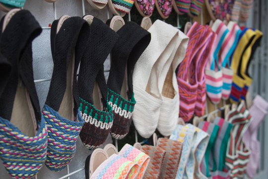 Handmade footwear. Handcraft colorful slippers on sale. Latin American artisans colorful crafted slippers hanged on the wall.