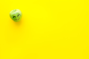 Emotion management concept. Happiness. Face drawn on apple. Yellow background top view copy space