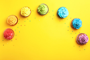Delicious birthday cupcakes on color background