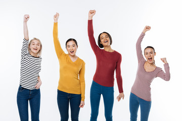 Fototapeta premium Absolute success. Nice positive young women standing together and feeling happy while celebrating their success