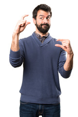 Handsome brunette man with beard making tiny sign on white background