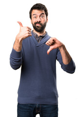 Handsome brunette man with beard making good-bad sign on white background