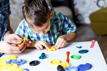 Picture of a boy playing with color play dough and cutters. Having fun with colorful modeling clay. Creative kids molding at home. Children play with plasticine or dough. 