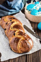 Homemade braided sweet bread with raisins on a wooden background