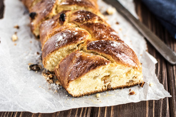 Homemade braided sweet bread with raisins on a wooden background