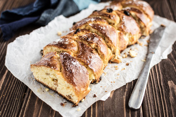 Homemade braided sweet bread with raisins on a wooden background