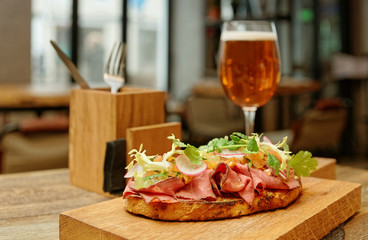 Sandwich with roast beef on restaurant table, toned, golden reflector