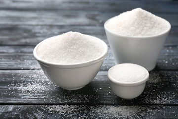 Ceramic bowls with pure sugar on wooden background