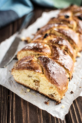 Homemade braided sweet bread with raisins on a wooden background