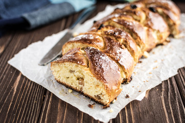 Homemade braided sweet bread with raisins on a wooden background