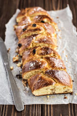 Homemade braided sweet bread with raisins on a wooden background