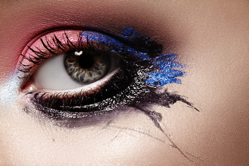 Closeup Female eyes with Bright Make-up. Great Halloween Look. Expression Makeup with Black, Pink and Dark Blue