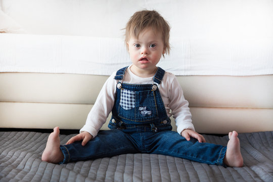 Portrait of cute baby boy with Down syndrome in home living room