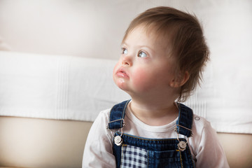 Portrait of cute baby boy with Down syndrome in home living room