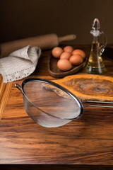 sieve, rolling pin, dough, egg, oil on wooden table