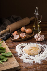 Fototapeta premium mug flour, eggs, rolling pin, olive oil in a jar on a wooden background, kneading