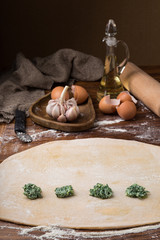 mug flour, eggs, rolling pin, olive oil in a jar on a wooden background, making ravioli