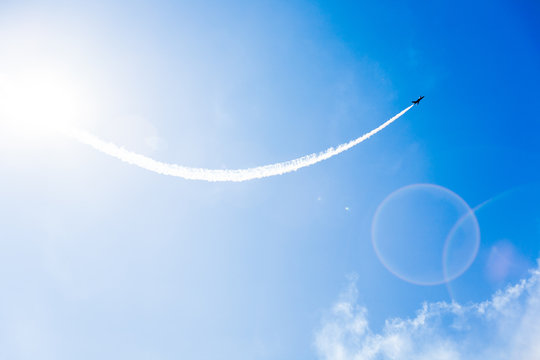 A group of professional pilots of military aircraft of fighters on a sunny clear day shows tricks in the blue sky, leaving beautiful traces of clouds scattered in different directions.