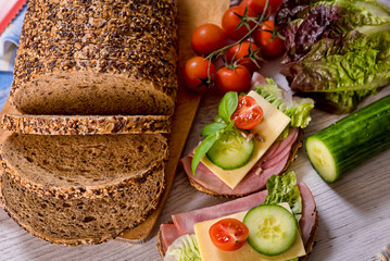 bread, fresh cereal bread with ham and vegetables, tasty healthy breakfast, top view, laid on the table
