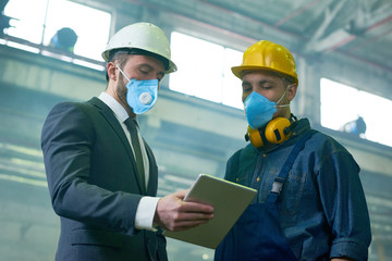 Fototapeta na wymiar Portrait of two engineers wearing protective masks and hardhats working at hazardous industrial plant, copy space