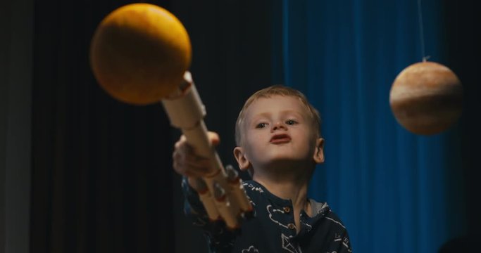 Little kid boy playing with toy space rocket, flying among planets. 4K UHD 