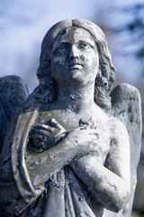 Fototapeta na wymiar Figure of a praying angel on a blue sky. Ancient statue.