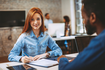 Young woman signing contract with manager