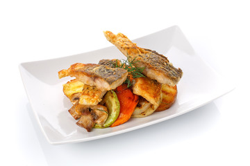 Fried fish with vegetables on a plate. Isolated on white