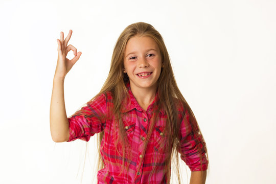 Young beautiful little girl smiles showing hand ok sign over white background