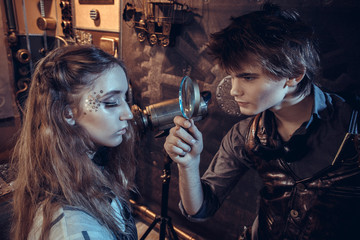  A young scientist looks at a girl in a magnifying glass.