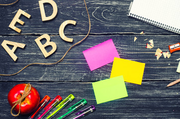A student's desk on a school board, a dark wooden background made of boards. Concept of education and school. Creative chaos. The office is on the table. Top view, space for text. Workplace.
