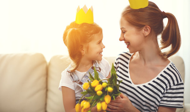 happy mother's day! mother and child daughter in crowns and with flowers .