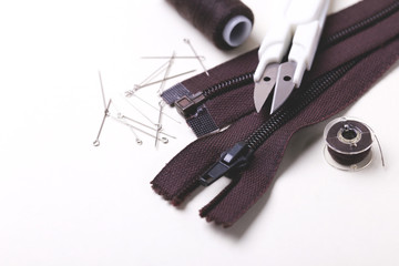 Sewing pins, scissors, zipper and plastic bobbin with colour threads
