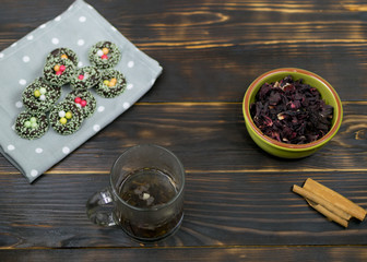 A cup with herbal tea and cookies on a dark background.