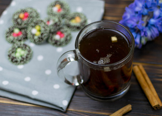 A cup with herbal tea and cookies on a dark background.