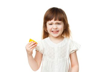 Girl 4-5 years crooked and eating lemon on white background