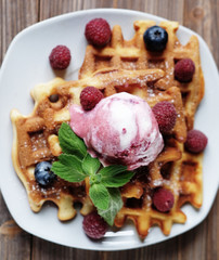 Plate of belgian waffles with ice cream and fresh berries - raspberries and blueberries.top view close-up.