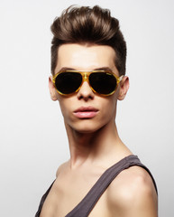 Fototapeta na wymiar Sexy young man in fashion style wearing sunglasses. Male model.