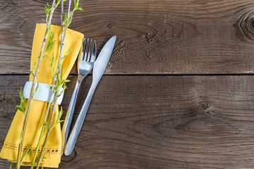 Table setting with yellow napkin and willow twigs on brown wooden table