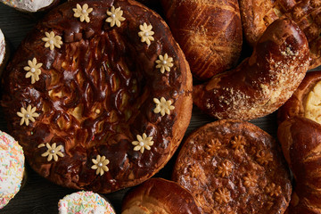 Traditional homemade Russian Easter baked goods, kulichi, patties with cottage cheese, karavai and loaf cake with nuts on festive table background