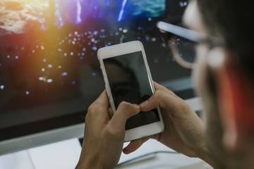 hands with the mobile phone on the desktop with the computer